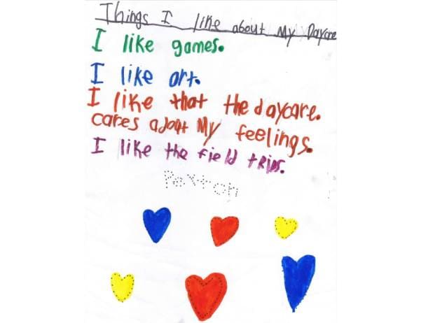 A child 's writing on paper with hearts.