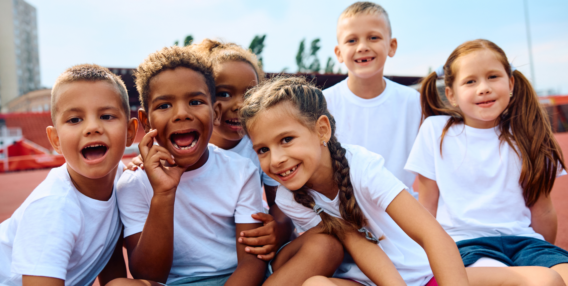 A group of children sitting together in front of trees.