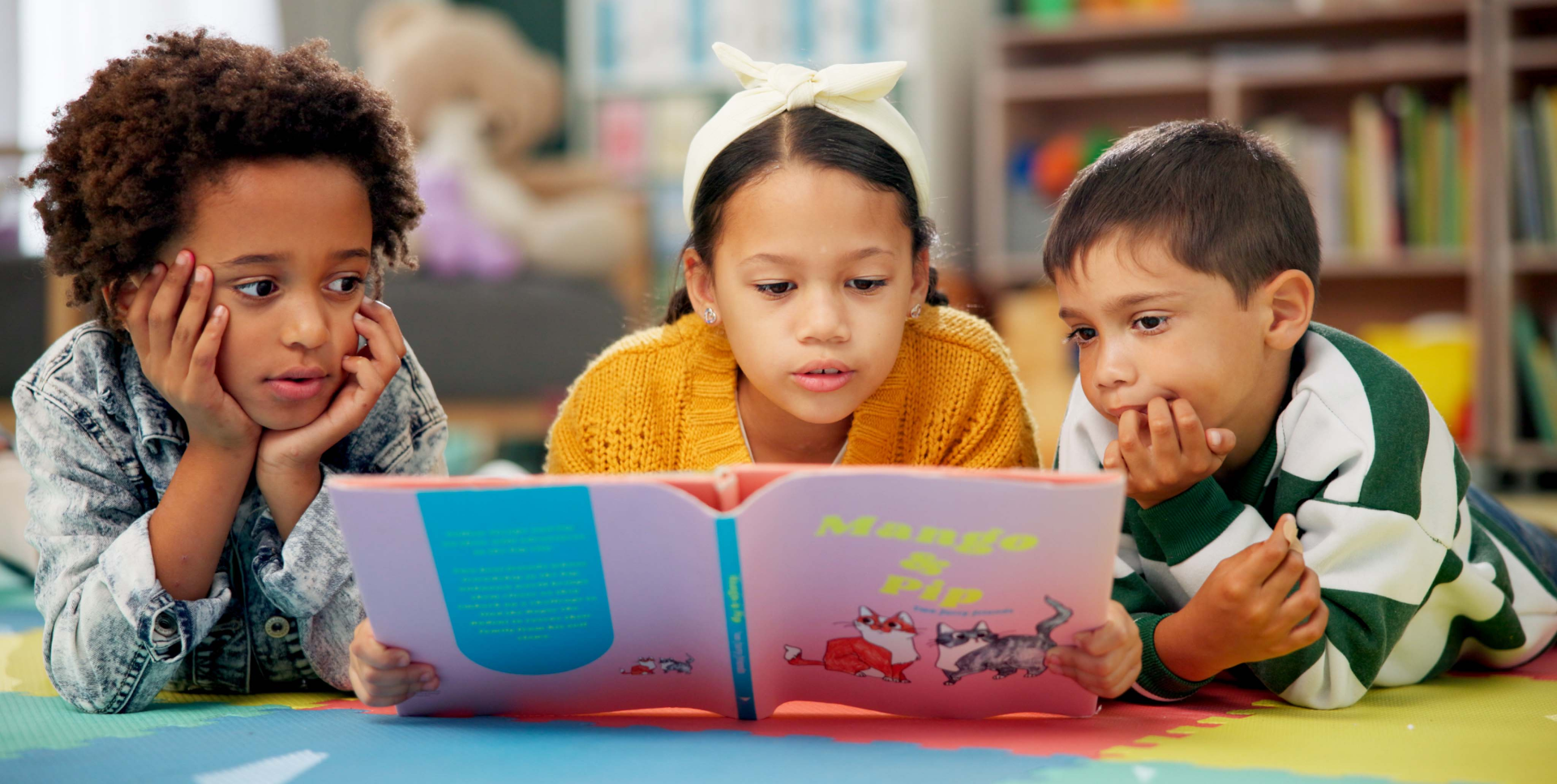 Three children are reading a book together.